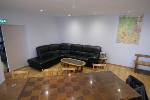 a living room with a black leather couch and a table at Gîte et Chambres d'hôtes du Musée Ecole in Le Monastier sur Gazeille