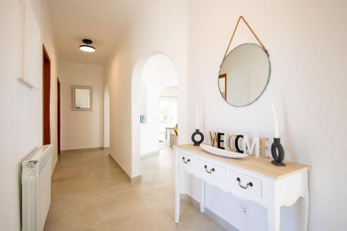 a hallway with a white dresser and a mirror at Pomba beautifully renovated with heated pool! in Poço Partido