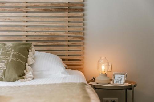 a bed with a wooden headboard and a table with a lamp at Huswell - Seaview apartment with spacious terrace in Zeebrugge in Zeebrugge