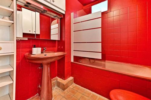 La salle de bains rouge est pourvue d'un lavabo et d'une baignoire. dans l'établissement Appartement parisien spacieux #Marais #Rivoli - II, à Paris