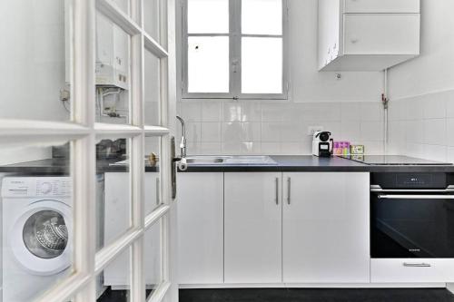 une cuisine blanche avec un évier et une machine à laver dans l'établissement Appartement parisien spacieux #Marais #Rivoli - II, à Paris