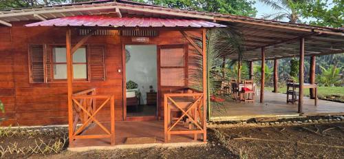 a small wooden cabin with a porch and a table at Gombela Ecolodge and Farming in São Tomé
