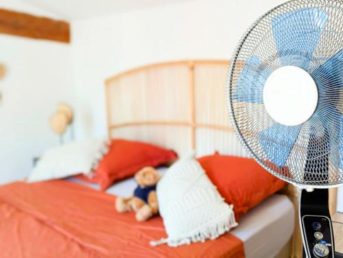 - un lit avec des oreillers rouges et blancs et un ventilateur dans l'établissement Le Cauris du pont romain, à Vaison-la-Romaine