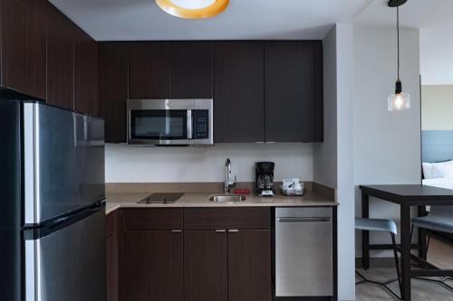 a kitchen with wooden cabinets and a stainless steel refrigerator at Residence Inn by Marriott Corpus Christi South in Corpus Christi