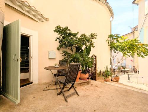 un patio avec une table, des chaises et des plantes dans l'établissement Le Cauris du pont romain, à Vaison-la-Romaine