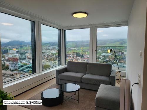 a living room with a couch and large windows at Park Tower City View Apartments in Zug