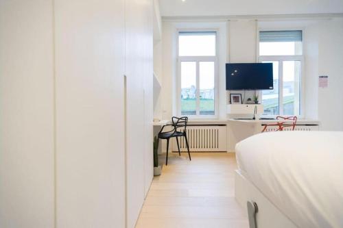 a bedroom with a bed and a desk with a tv at Studio Fischer à la Pétrusse 302 in Luxembourg