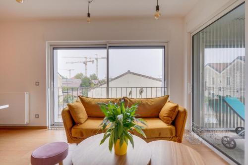 un salon avec un canapé et une grande fenêtre dans l'établissement MDOR Le Darwin - Terrasse et parking privé, à Bordeaux