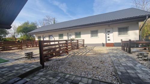 a white house with a fence and a gate at Sarudi Wellness Apartman in Sarud