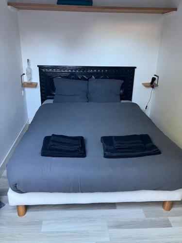 - une chambre avec un grand lit et 2 serviettes noires dans l'établissement Appartement Doëlan, le port et la mer à pieds, à Clohars-Carnoët