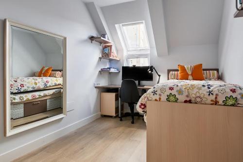 a bedroom with a bed and a desk and a mirror at Alojamiento NUEVO en el centro de León - Edificio RVM in León