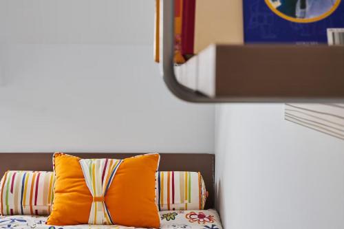 a couch with an orange pillow and a mirror at Alojamiento NUEVO en el centro de León - Edificio RVM in León