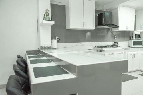 a white kitchen with white cabinets and black chairs at Modern & Best Location Airport US Embassy Boarder in Tijuana