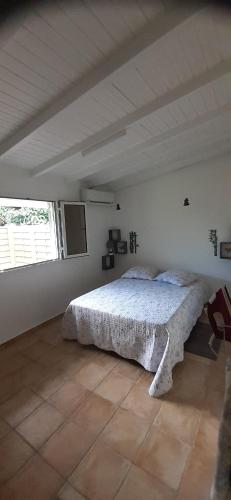 une chambre avec un lit dans une pièce blanche dans l'établissement L'IXORA des îles, à Le Moule
