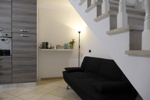 a living room with a black couch and a floor lamp at Casa di Nonna Rosa in Benevento