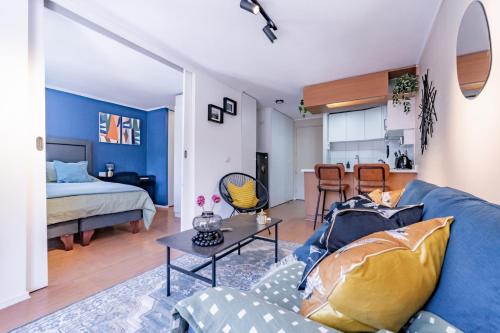 a living room with a blue couch and a bed at San Carlos rentals - Lastarria in Santiago