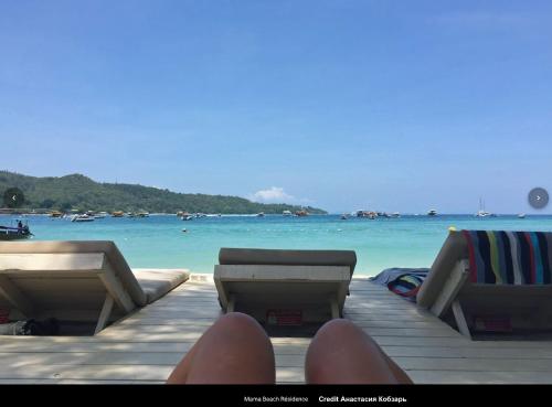 a person sitting on a dock near the ocean at Mama Beach Residence - Adults Only in Phi Phi Don