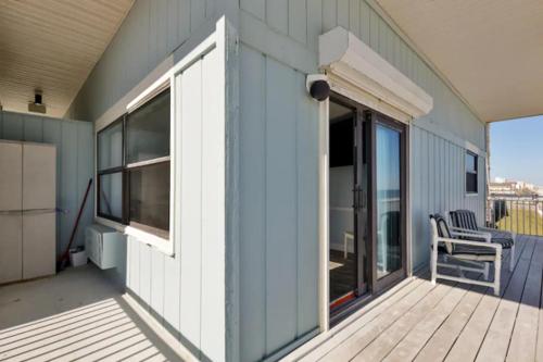 a blue house with a deck with a chair on it at Coastal Waters in New Smyrna Beach