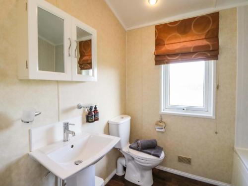 a bathroom with a sink and a toilet and a window at Crathie Lodge in Fort William