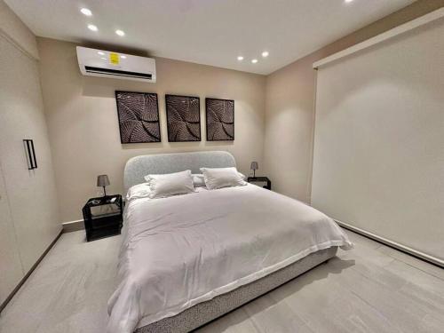 a bedroom with a large white bed with two pictures on the wall at Elegant 5-Bedroom Apartment in Exclusive Playa Escondida Pet Friendly in María Chiquita