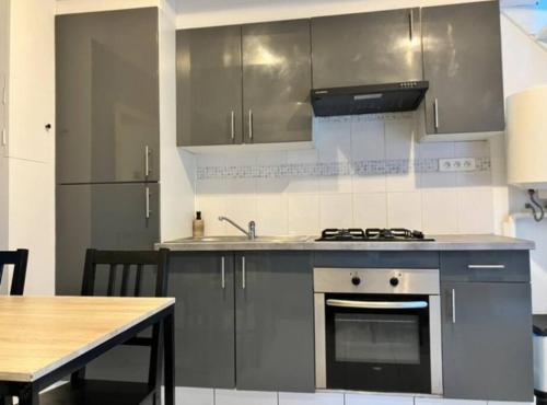 une cuisine avec des appareils en acier inoxydable et une table dans l'établissement Appartement proche de la mer, à Clohars-Carnoët