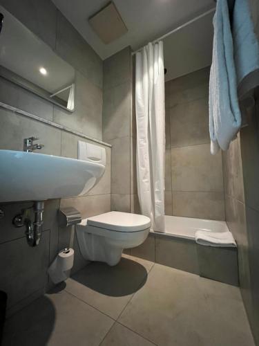 a bathroom with a sink and a toilet and a tub at Hotel Monopol City Centre in Düsseldorf