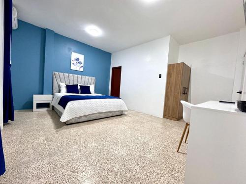a bedroom with a bed and a blue wall at SC Central Suite in Manta