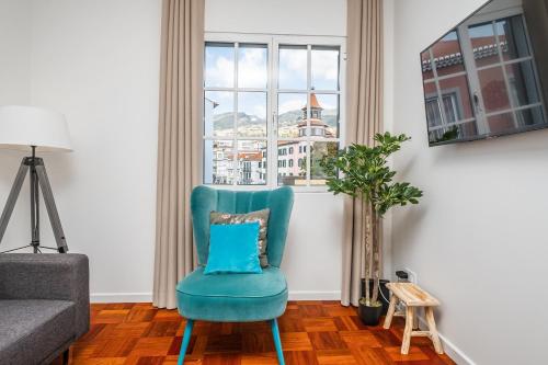 a blue chair in a living room with a window at Ribeira do Esmeraldo by Homie in Funchal