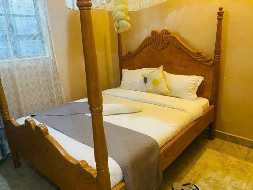 a bedroom with a four poster bed with white sheets at Villa Serene Hotel in Kitale