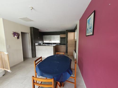 une cuisine avec une table, des chaises et un mur violet dans l'établissement Le refuge de Montesquieu, à Montesquieu-Lauragais