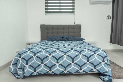 a bed with a blue and white comforter in a bedroom at Modern & Best Location Airport US Embassy Boarder in Tijuana