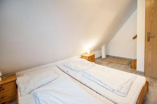 a white bed in a room with a light on it at Haus Konstantin in Neßmersiel
