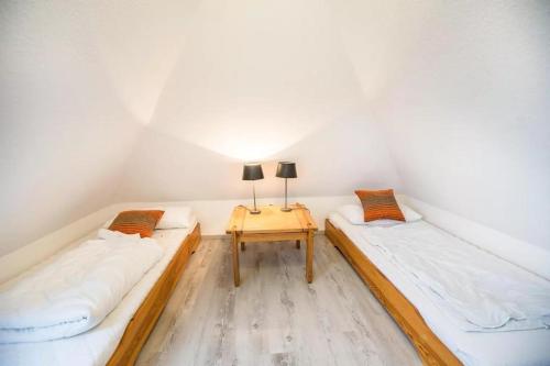two twin beds in a room with a table at Haus Konstantin in Neßmersiel