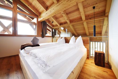 a large white bed in a room with wooden ceilings at Grieserhof Nals in Nalles