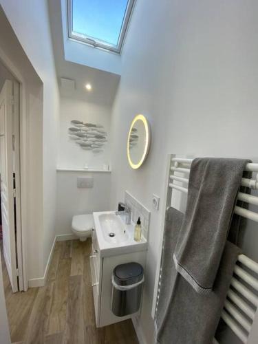 une salle de bain blanche avec un lavabo et un miroir dans l'établissement Sweat little home close to Sword beach, à Ouistreham