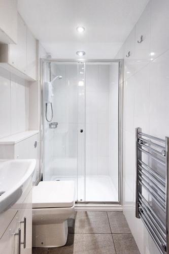 a white bathroom with a shower and a toilet at 1 Bed flat in East Dulwich in London