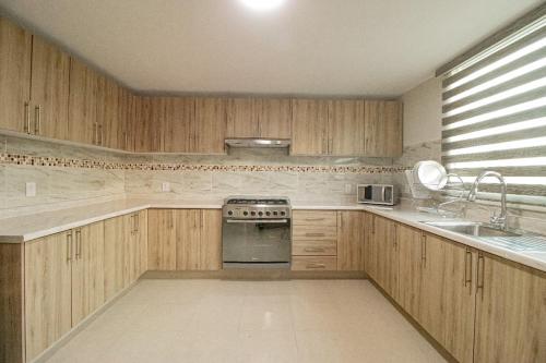 a kitchen with wooden cabinets and a sink and a stove at Memora Hotel & Villas Chapala in Chapala