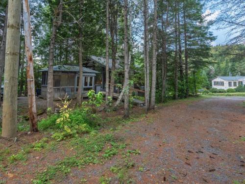 an image of a house in the woods with a driveway at Le1603 - Le Petit Caribou - Chalet spa et plage in Sainte-Lucie-de-Doncaster