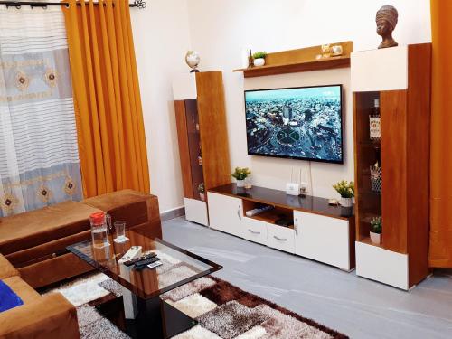 a living room with a television on a wall at Appartement Cosy & Chill avec Groupe Electrogène, Forage, Parking, Gardien et WiFi in Douala