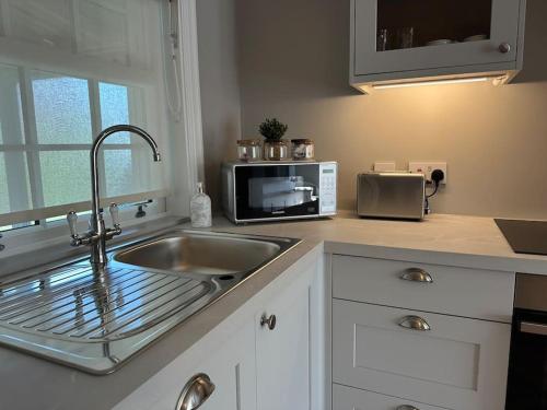 a kitchen with a sink and a microwave at Stunning new Duplex apartment - Christchurch in Christchurch