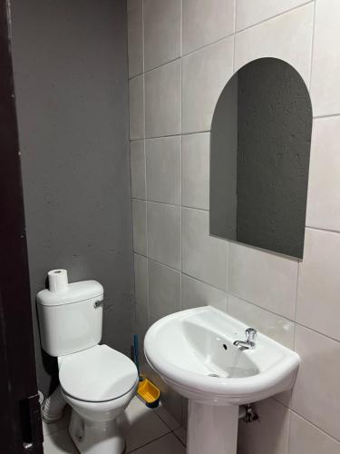 a bathroom with a white toilet and a sink at Família BnB in Tekwane