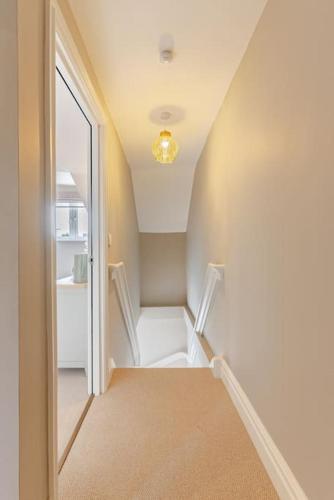 a hallway with a staircase with a mirror and a door at Stunning new Duplex apartment - Christchurch in Christchurch