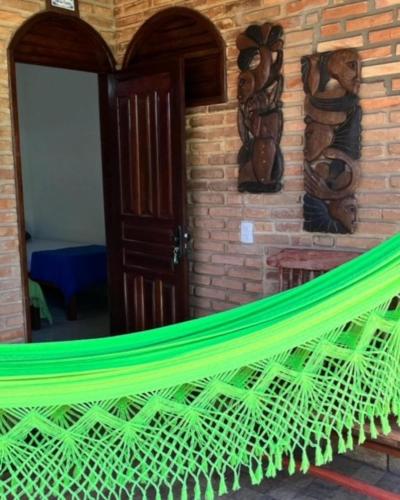 Una hamaca verde en una habitación con una pared de ladrillos. en Recanto das Flores Suíte Master 2, en Barra de Santo Antônio