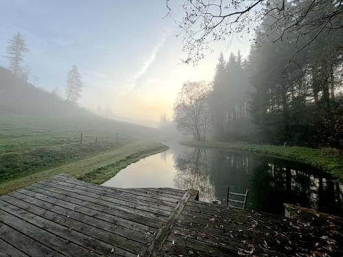 a misty river with a wooden bridge in the middle at Mein Landhaus I Die Bachklanghütte in Sankt Veit in der Gegend