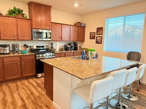 a kitchen with wooden cabinets and a counter with white chairs at #stayRioVista -Country Club House with Hot Tub-Sauna-Firepit-Garden-Games in Rio Vista