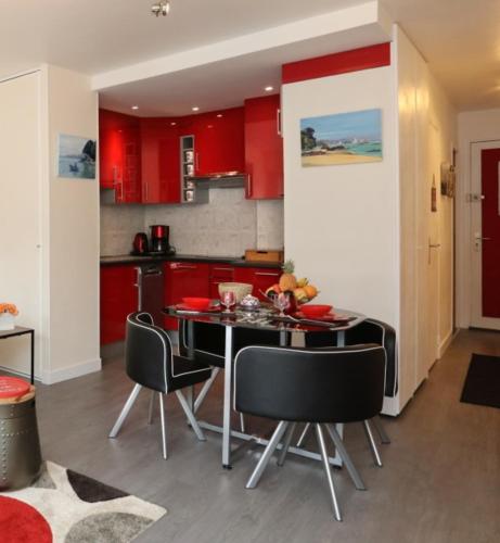 une cuisine avec des armoires rouges et une table et des chaises dans l'établissement Studio résidence les gémeaux, à Quiberon