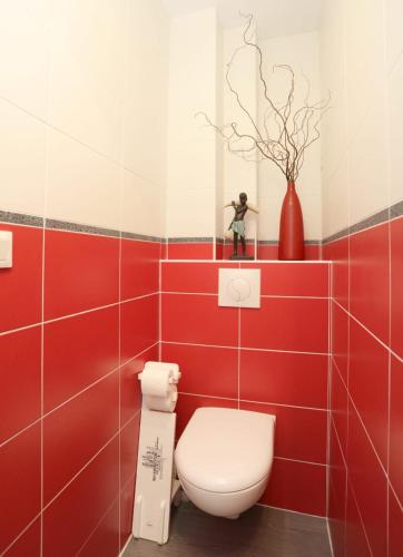 - une salle de bains rouge et blanche avec des toilettes et un vase dans l'établissement Studio résidence les gémeaux, à Quiberon