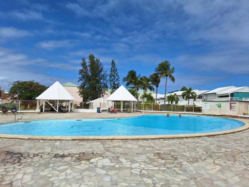 a large blue swimming pool with white umbrellas at Chez Marine ô Marines in Saint-François