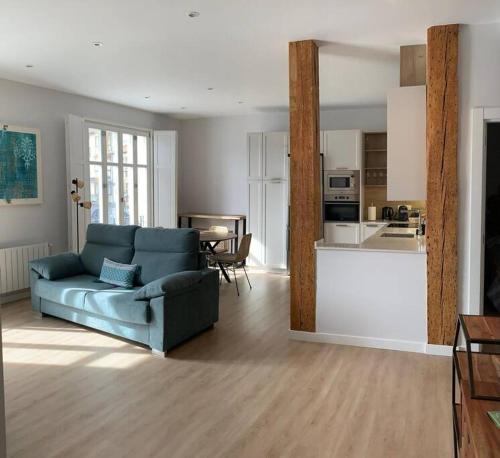 a living room with a blue couch and a kitchen at Luminoso piso con vistas al Puerto in Castro-Urdiales