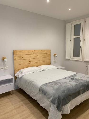 a white bedroom with a large bed and a window at Luminoso piso con vistas al Puerto in Castro-Urdiales